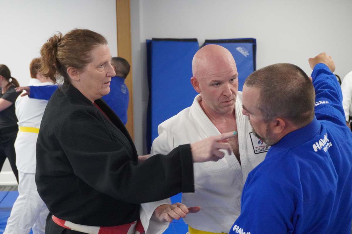 Sensei Debbie Burk (left) pointing out hand placements after a block with Dominic Russo (foreground) and Christopter Lewis (Background).